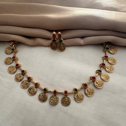 Gold necklace with embedded stones on a light fabric background