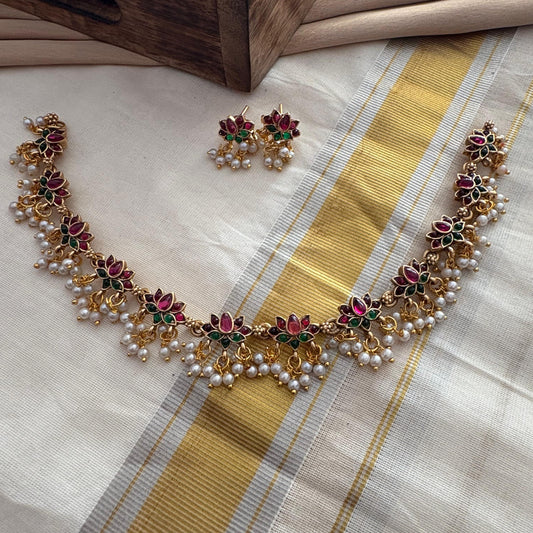 Necklace and earrings set on a saree fabric with a wooden box in the background