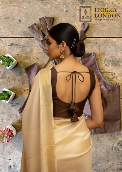 Lioraa London Ltd brown silk blouse with deep U-back, tie-up detail, and padded sleeves worn with a cream saree.